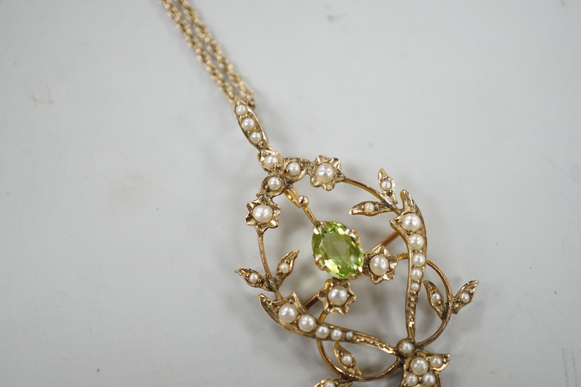 An Edwardian 9ct, peridot and seed pearl set drop pendant brooch, 57mm, on a later 375 rope twist chain, 44cm gross weight 6.7 grams.